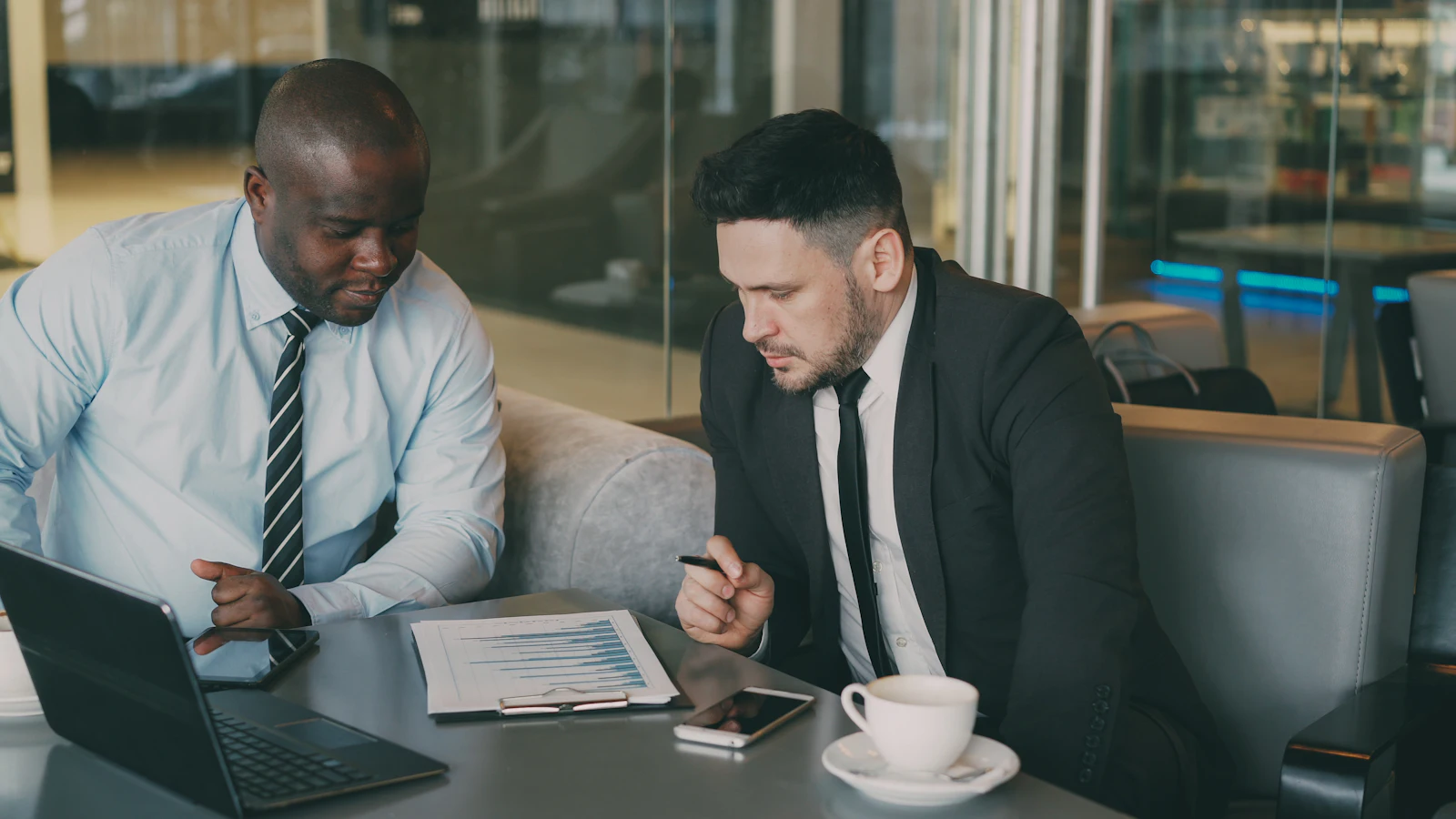 Two advisers reviewing a printed report beside a laptop.
