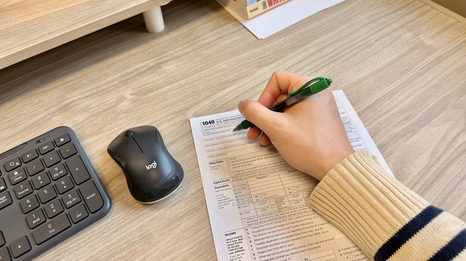 A hand filling in and signing a paper form at a desk.